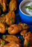 A platter of wings and ranch sauce for dipping.