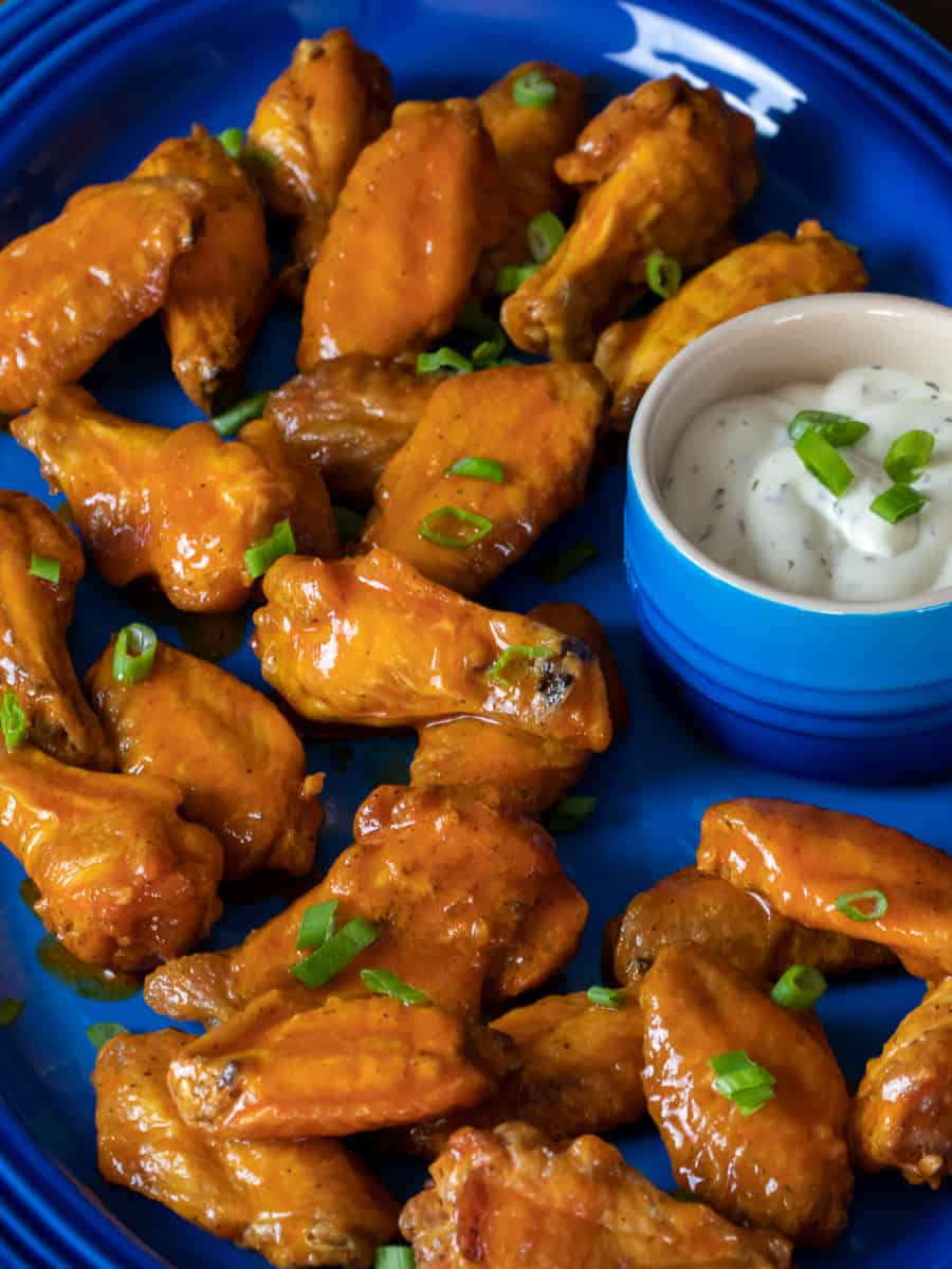 A tall image of wings tossed in buffalo sauce.
