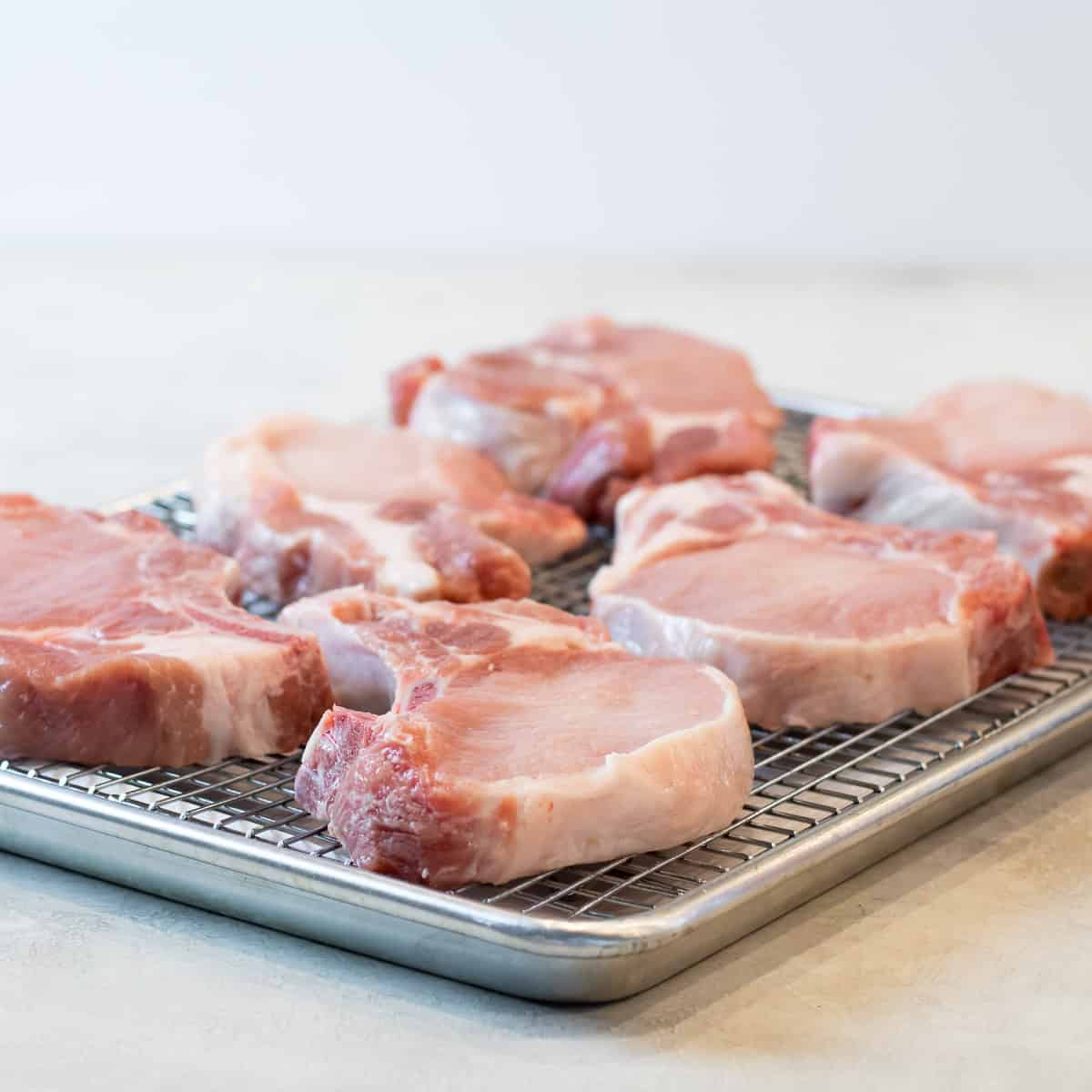 A baking sheet with rack and bone-in chops.
