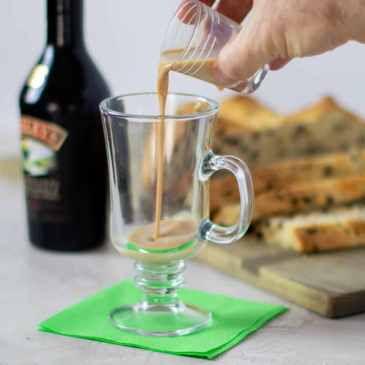 Pouring Irish cream in the glass mug.