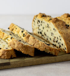 A fresh loaf of bread that is sliced on a serving board.