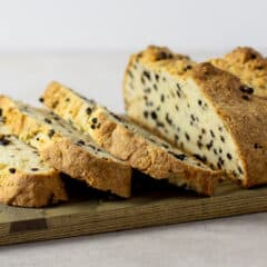 A fresh loaf of bread that is sliced on a serving board.