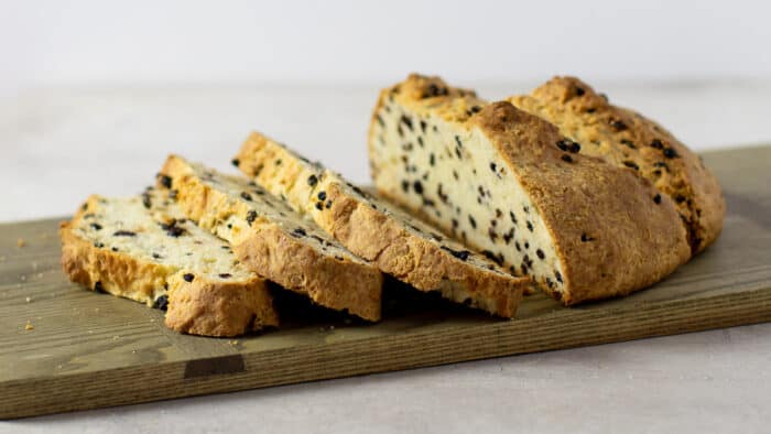 A fresh loaf of bread that is sliced on a serving board.