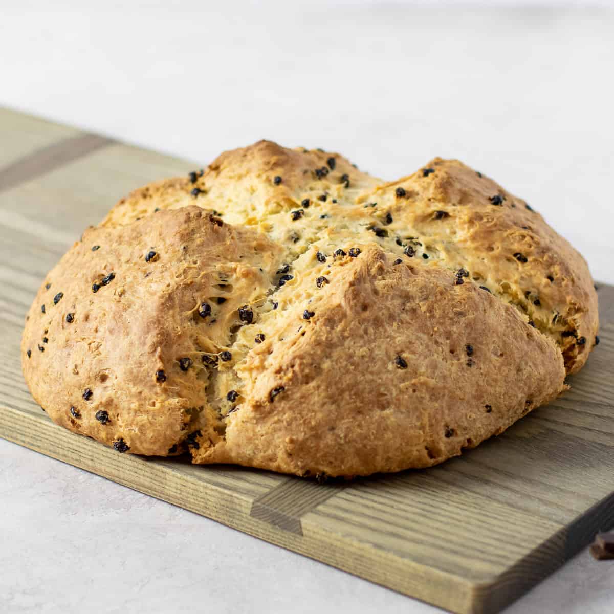 Finished loaf of baked bread on a cutting board.