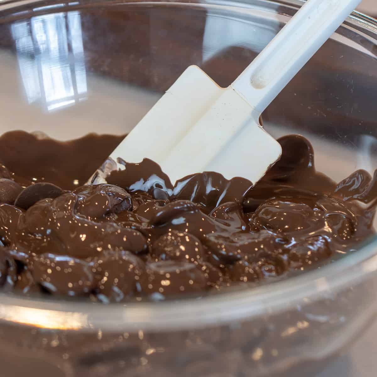 A bowl of melted candy melts stirred with a rubber spatula.
