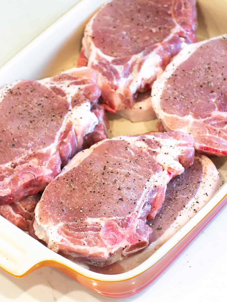 Seasoned pork rib chops in a dish.