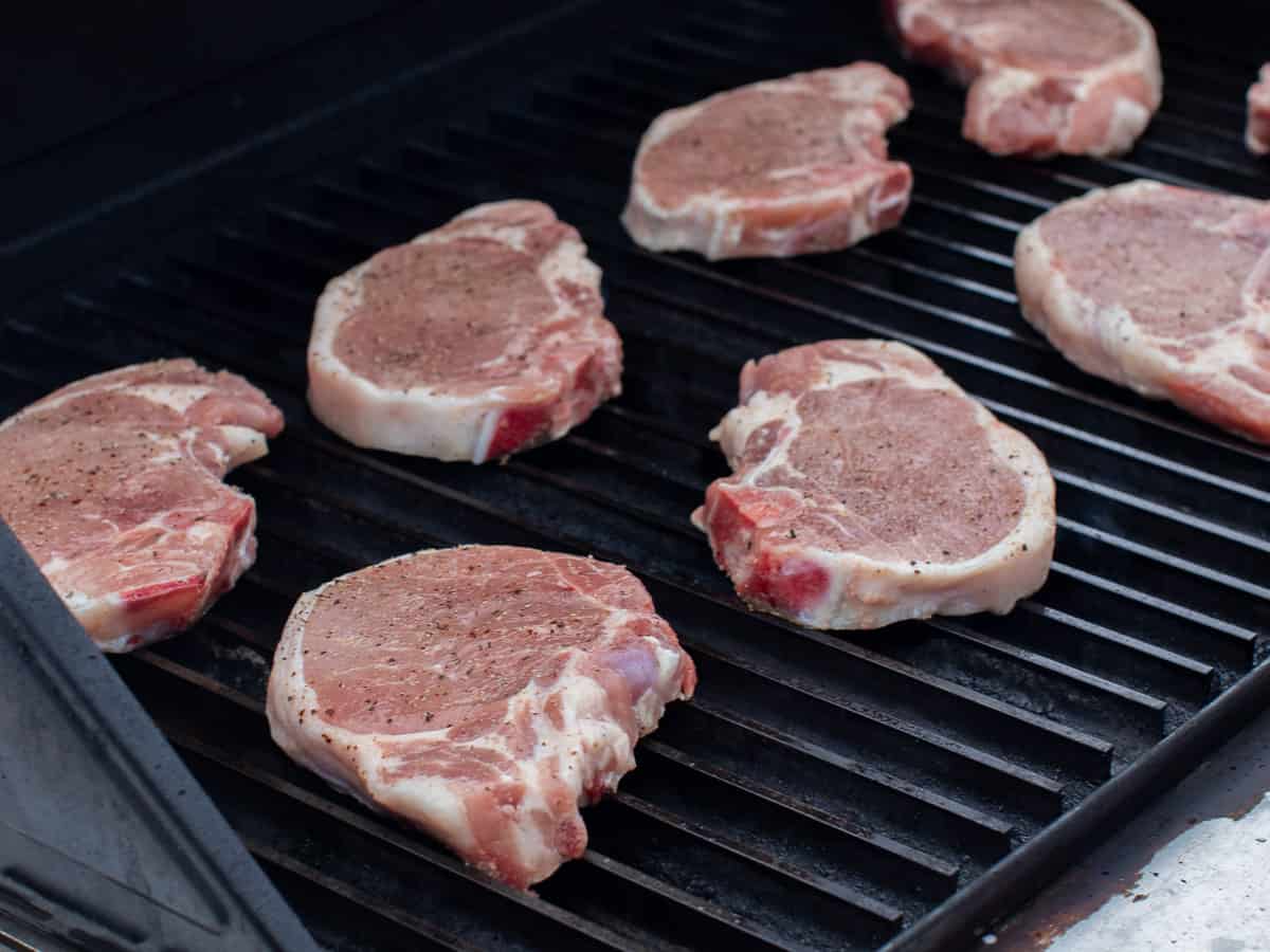 Raw seasoned chops on a grill.