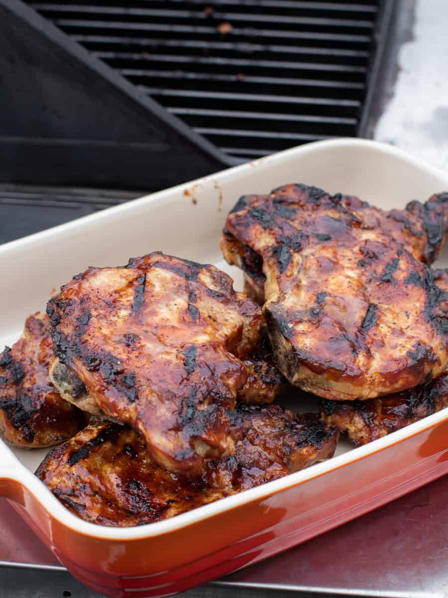 A serving dish of cooked pork chops with lots of BBQ sauce.