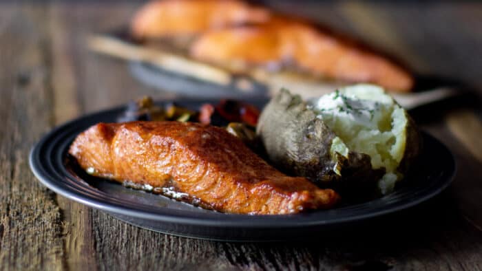 A plate of grilled salmon and a baked potato.