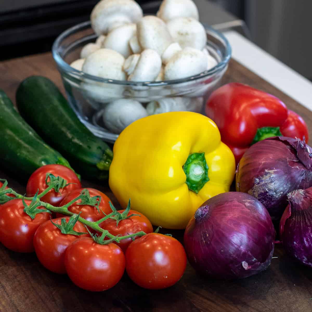 A collection of whole raw vegetables on a cutting board.