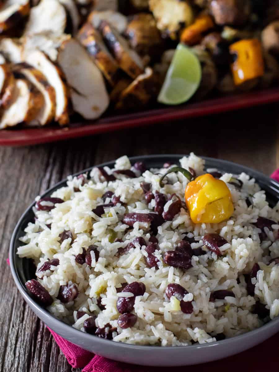 An overhead picture of a bowl with rice and beans and a platter of chicken and vegetables.