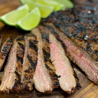 Flank Steak on a cutting board with lime wedges.