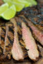 Flank Steak on a cutting board with lime wedges.