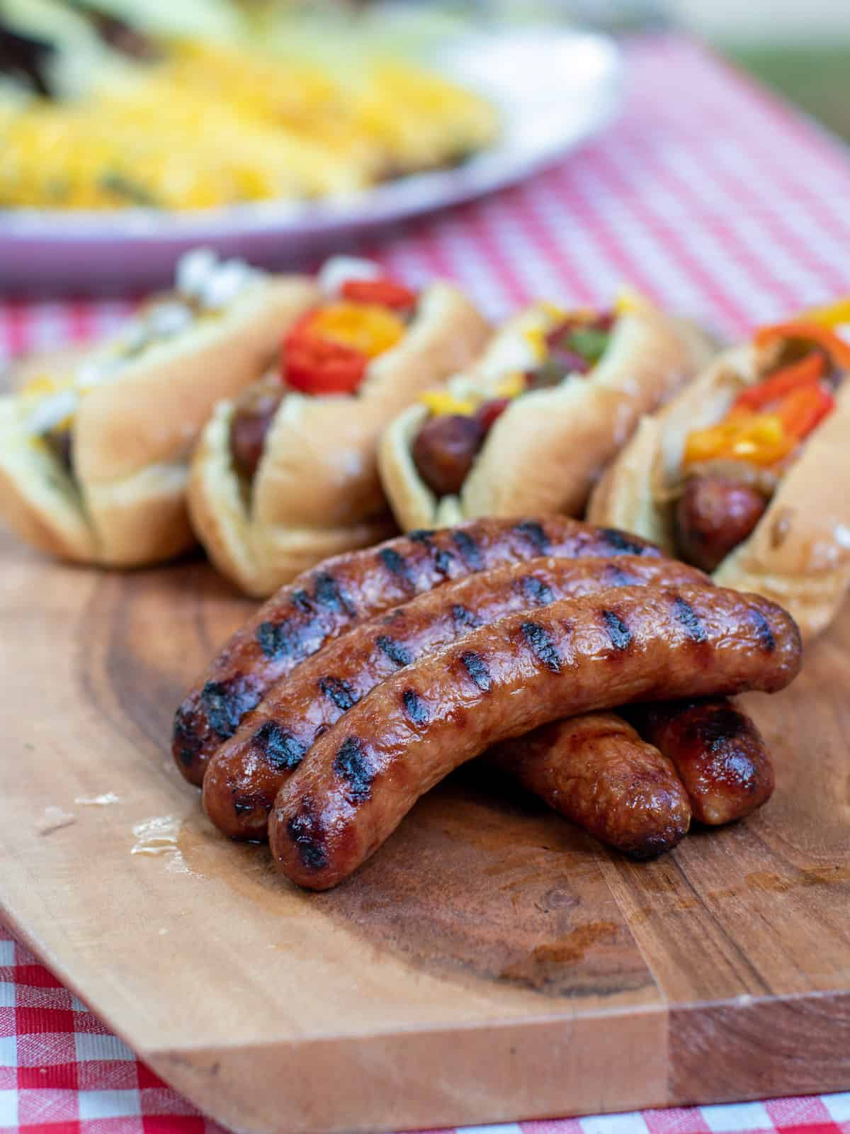 A picnic with sausages on a bun and corn on the cob.