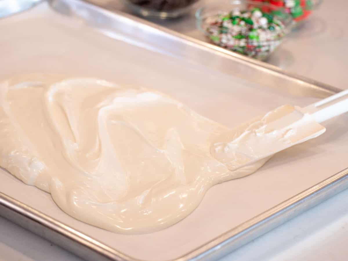 Melted white chocolate being spread on a baking sheet.