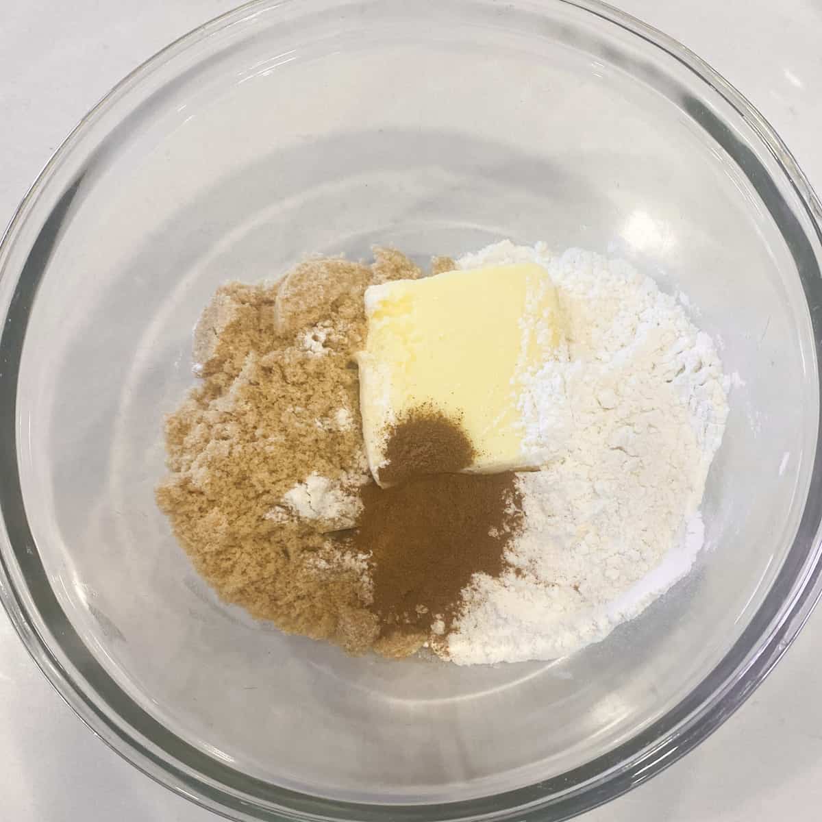 A glass bowl with butter, brown sugar, flour and cinnamon.