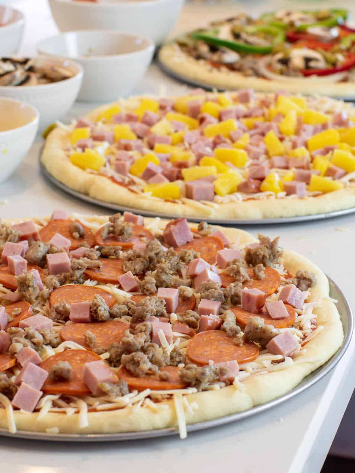 Three pizzas ready to go in the oven.