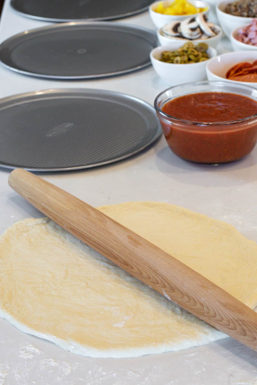 A rolling pin on a rolled out pizza dough.