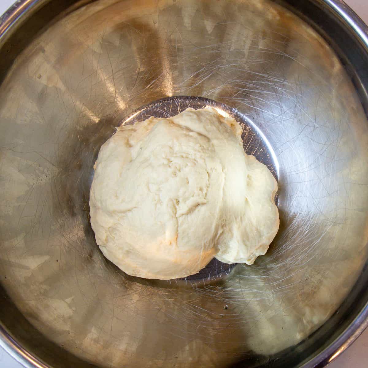 Freshly kneaded dough in a greased bowl.