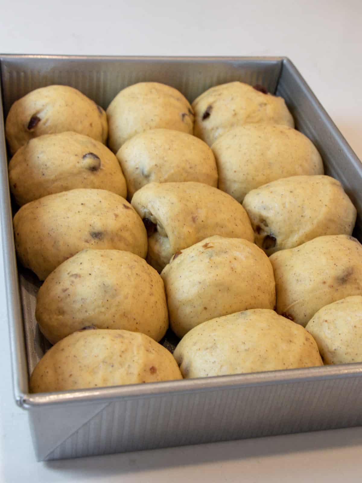 Risen rolls of dough in a baking dish.