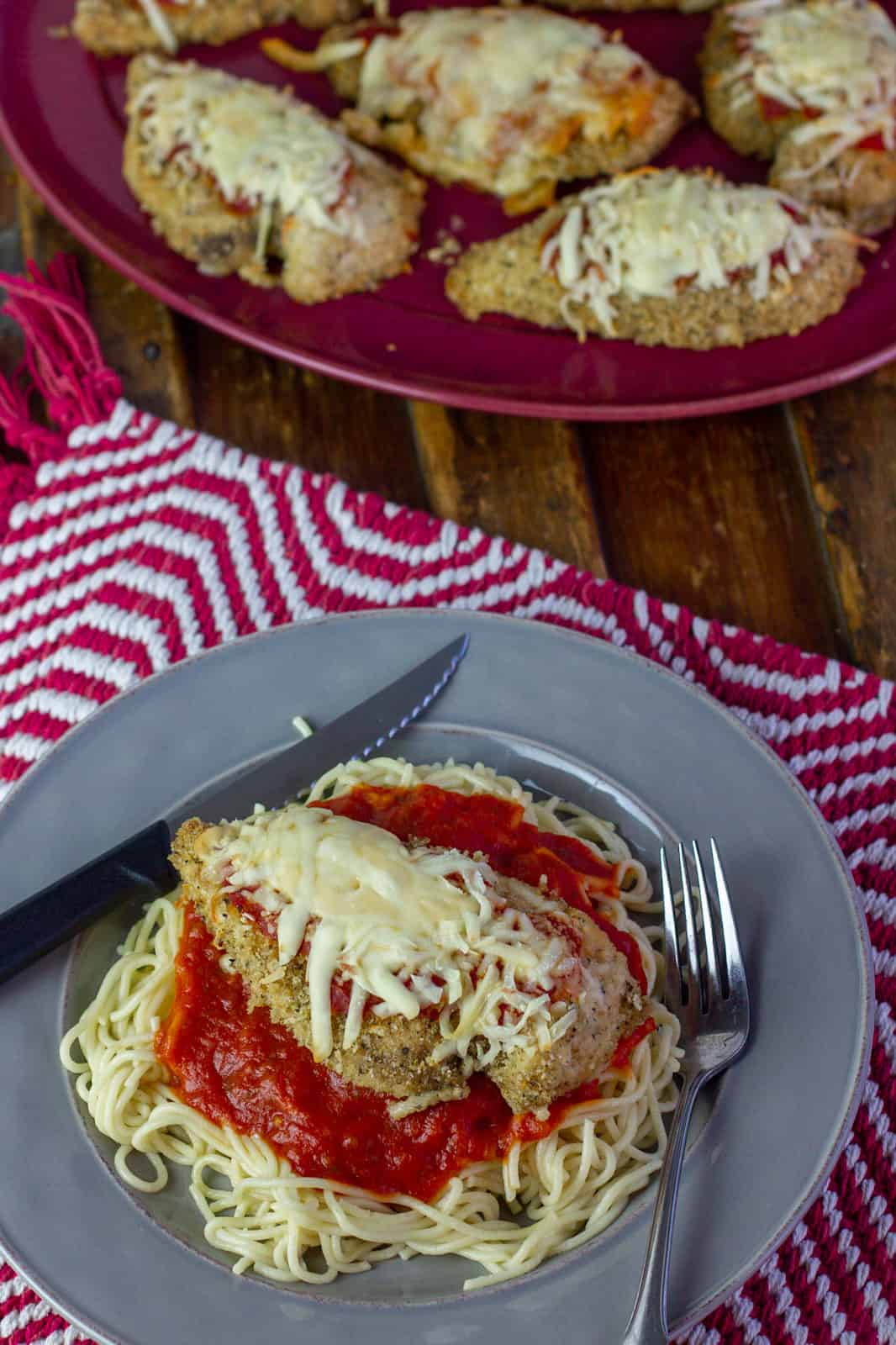 An over head picture of a plate of chicken parmesan next to a plate with more chicken.