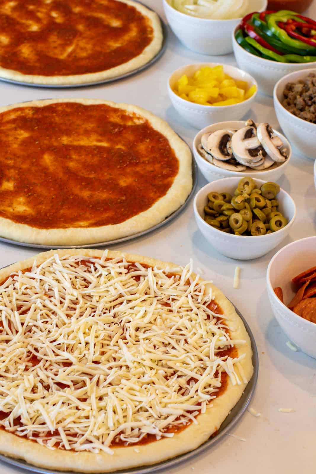 Over head image of assembling three pizzas.