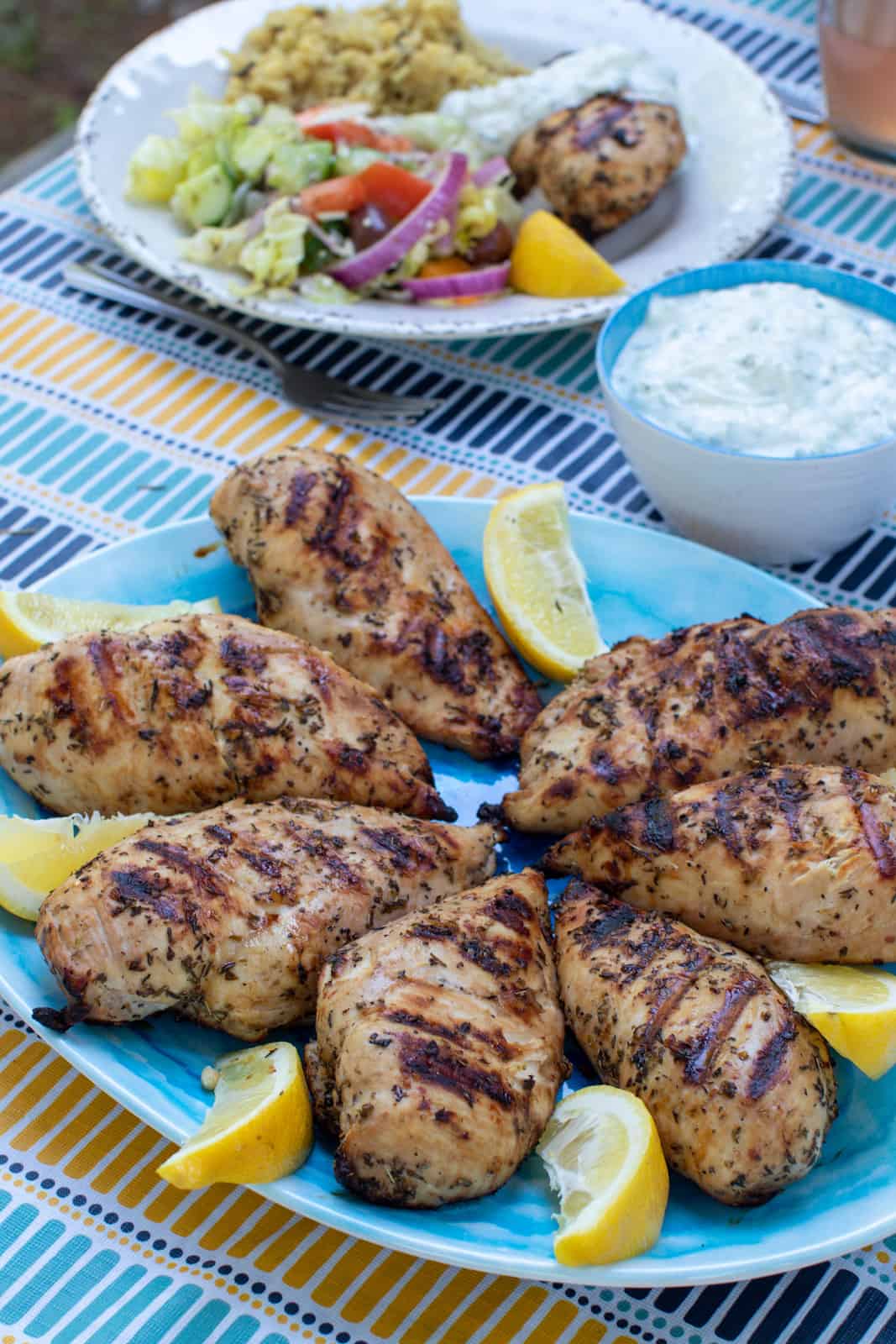 A platter of Grilled Greek Chicken with lemon slices.