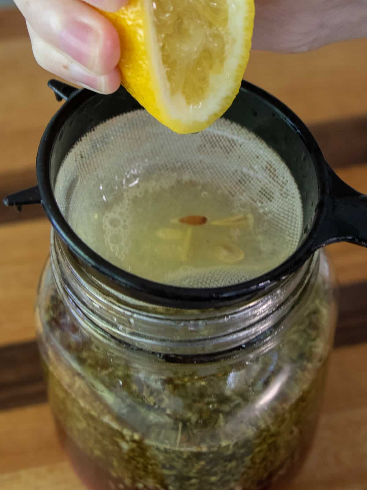 Squeezing some lime juice through a strainer to catch the seeds.