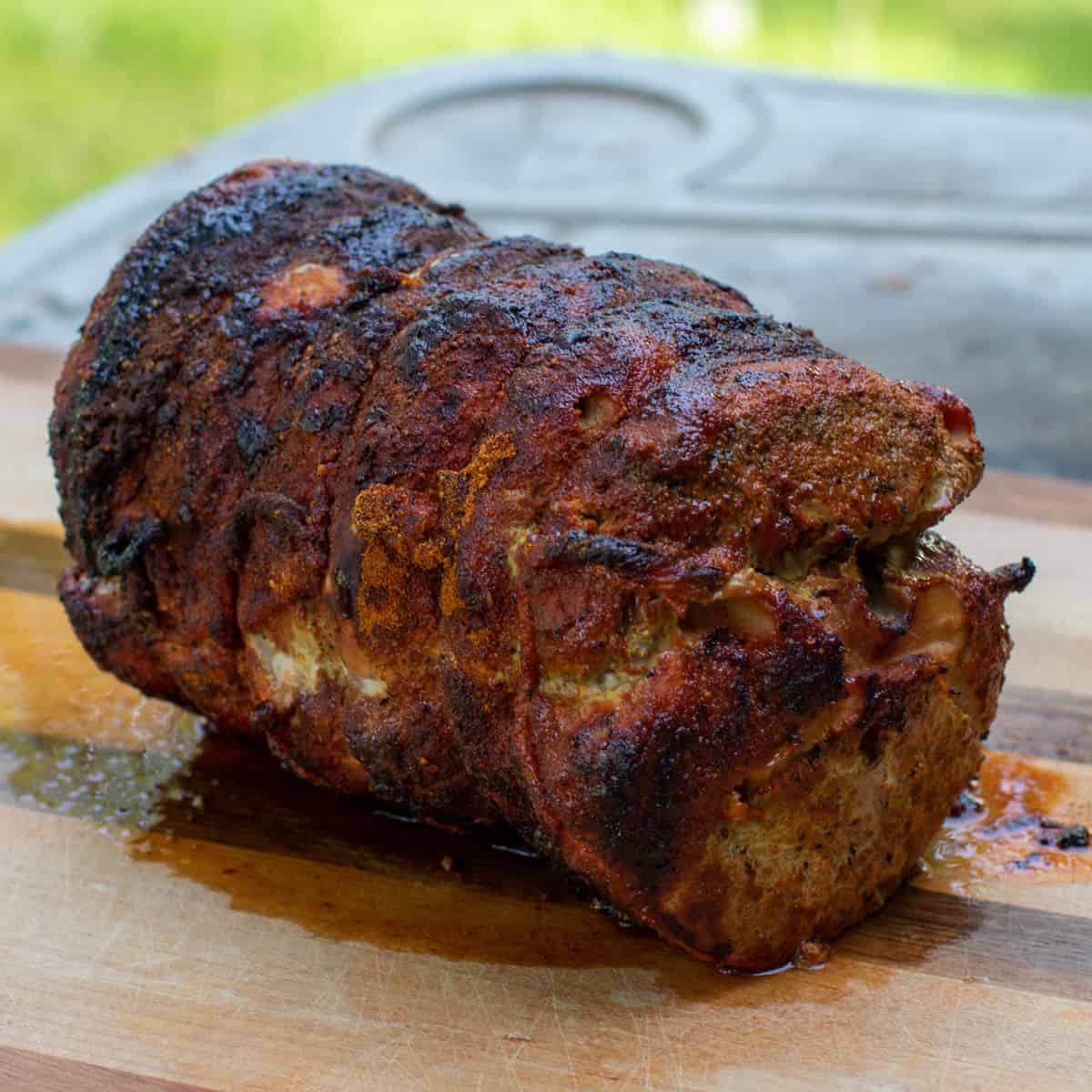 Grilled pork roast resting on a cutting board.