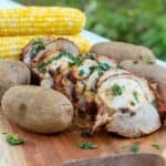 A serving platter with pork roast, potatoes and corn.