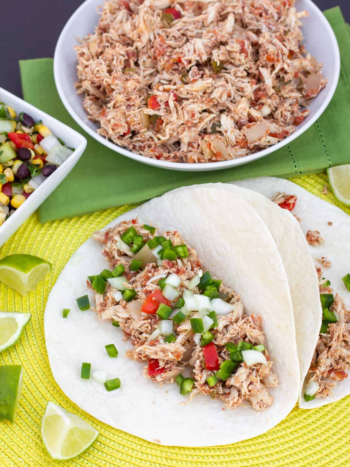 Slow cooker chicken carnitas topped with diced peppers and onions.