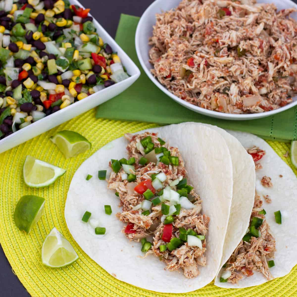 Overhead picture of chicken carnitas next to a bowl of black bean and corn salad