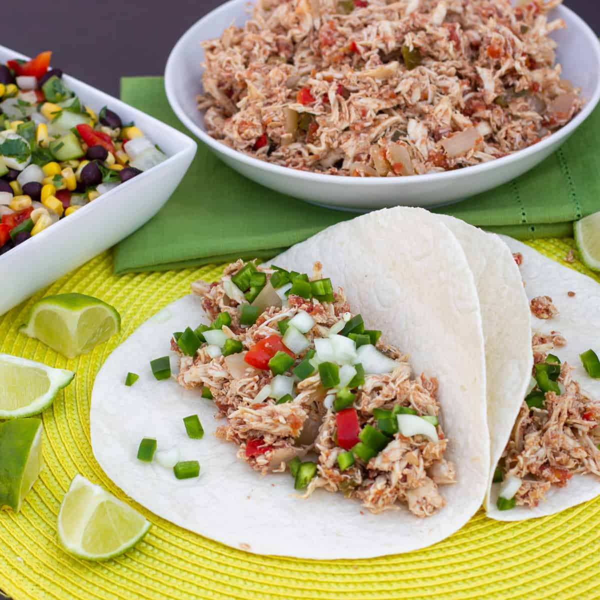 A bowl of shredded chicken and two carnitas.