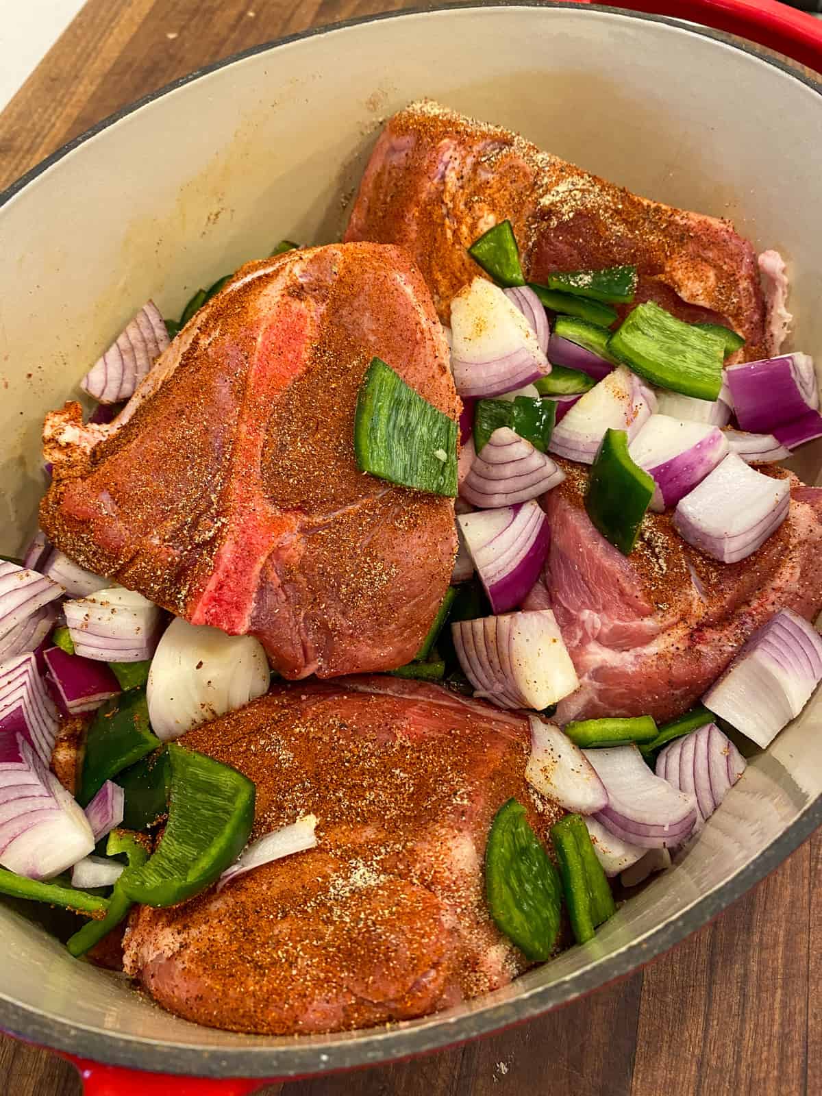 Seasoned pork roast, onions and peppers in a dutch oven.