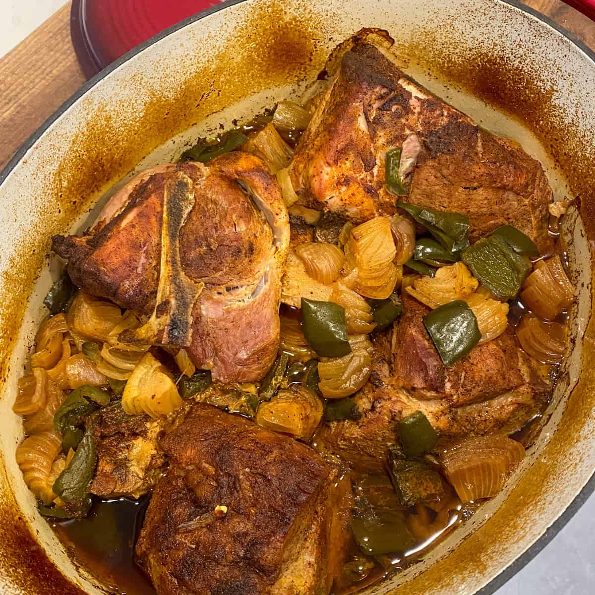 Cooked pork in a dutch oven, that is ready to be pulled.