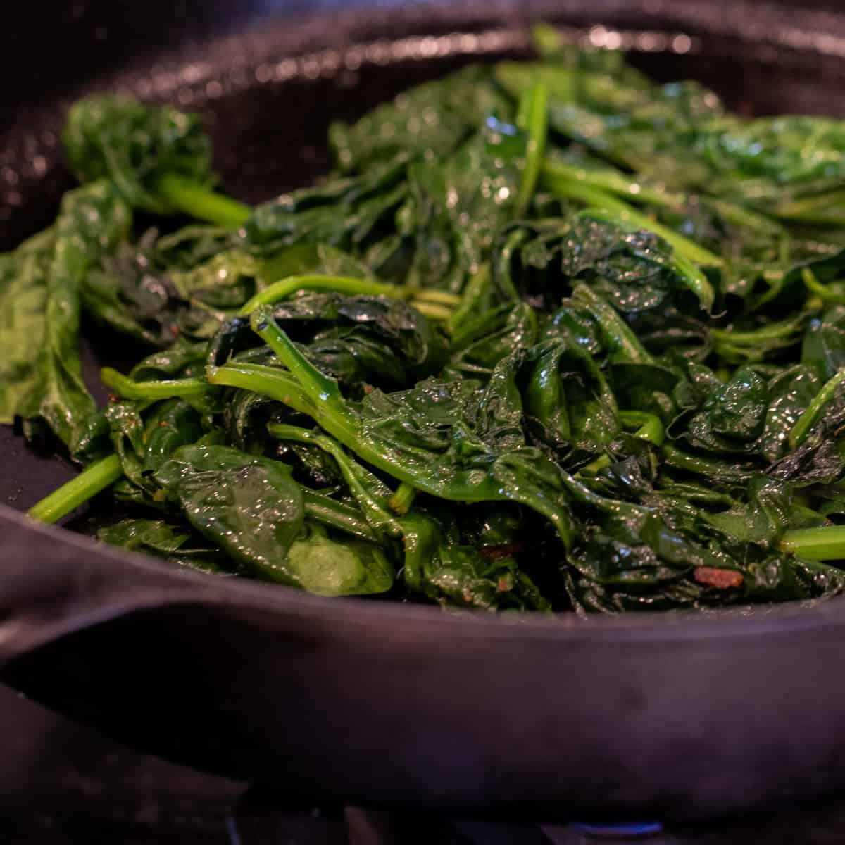 Cooked spinach in a cast iron pan.