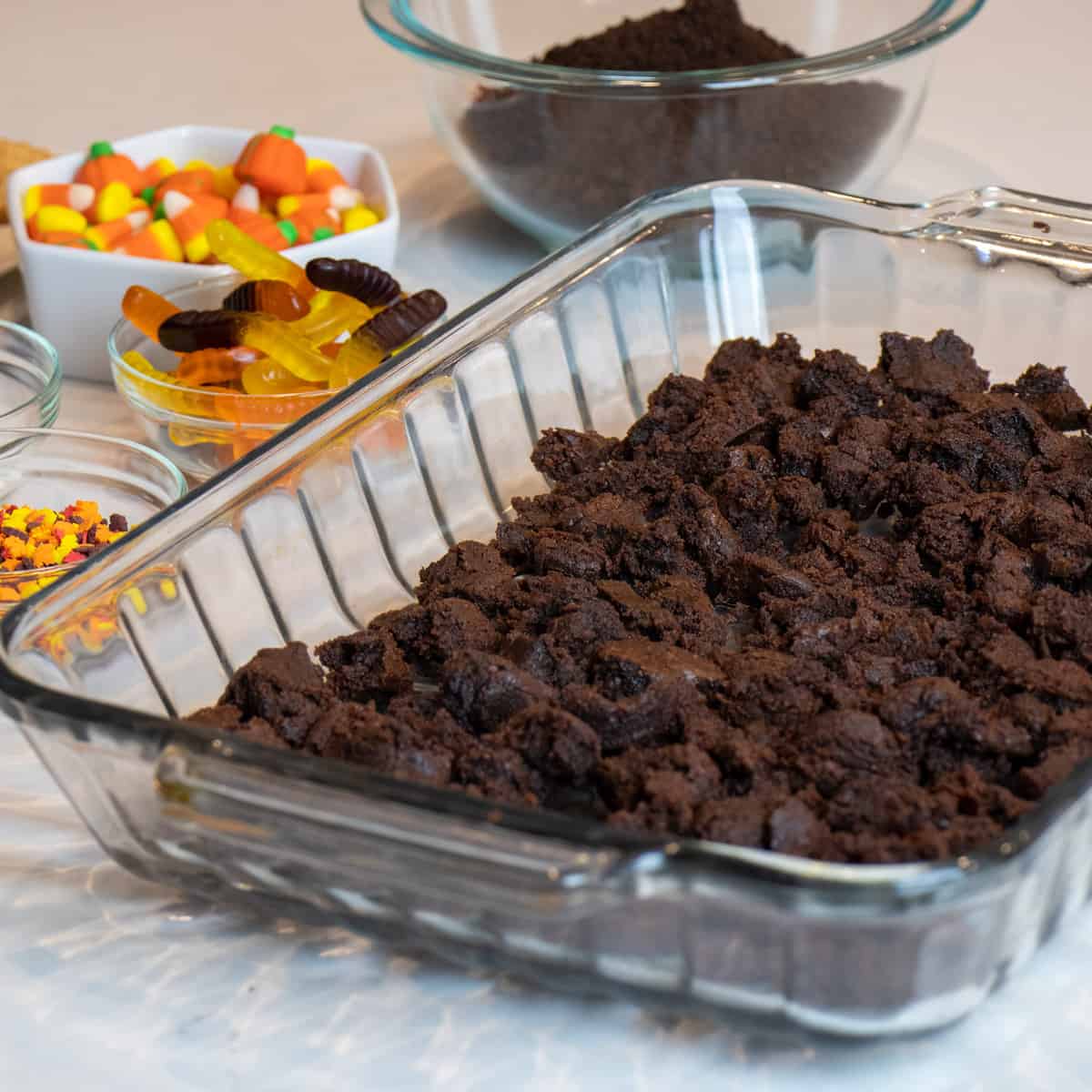 A layer of two bite mini brownies crumbled and spread across a baking dish.