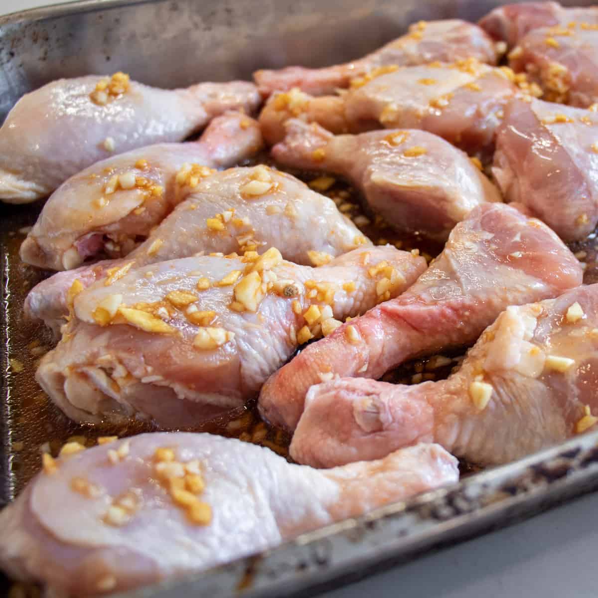 Raw chicken drumsticks in a baking pan.