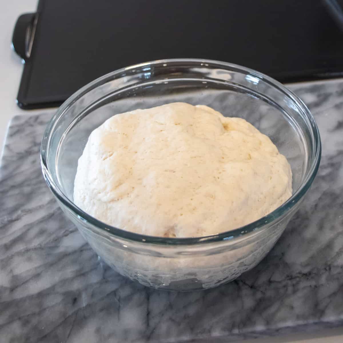 Fresh risen dough in a glass bowl.
