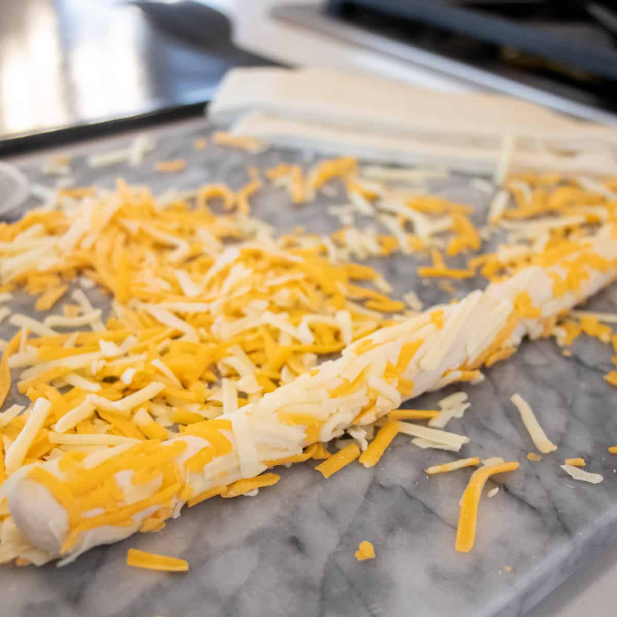 A raw breadstick rolled in grated cheese.