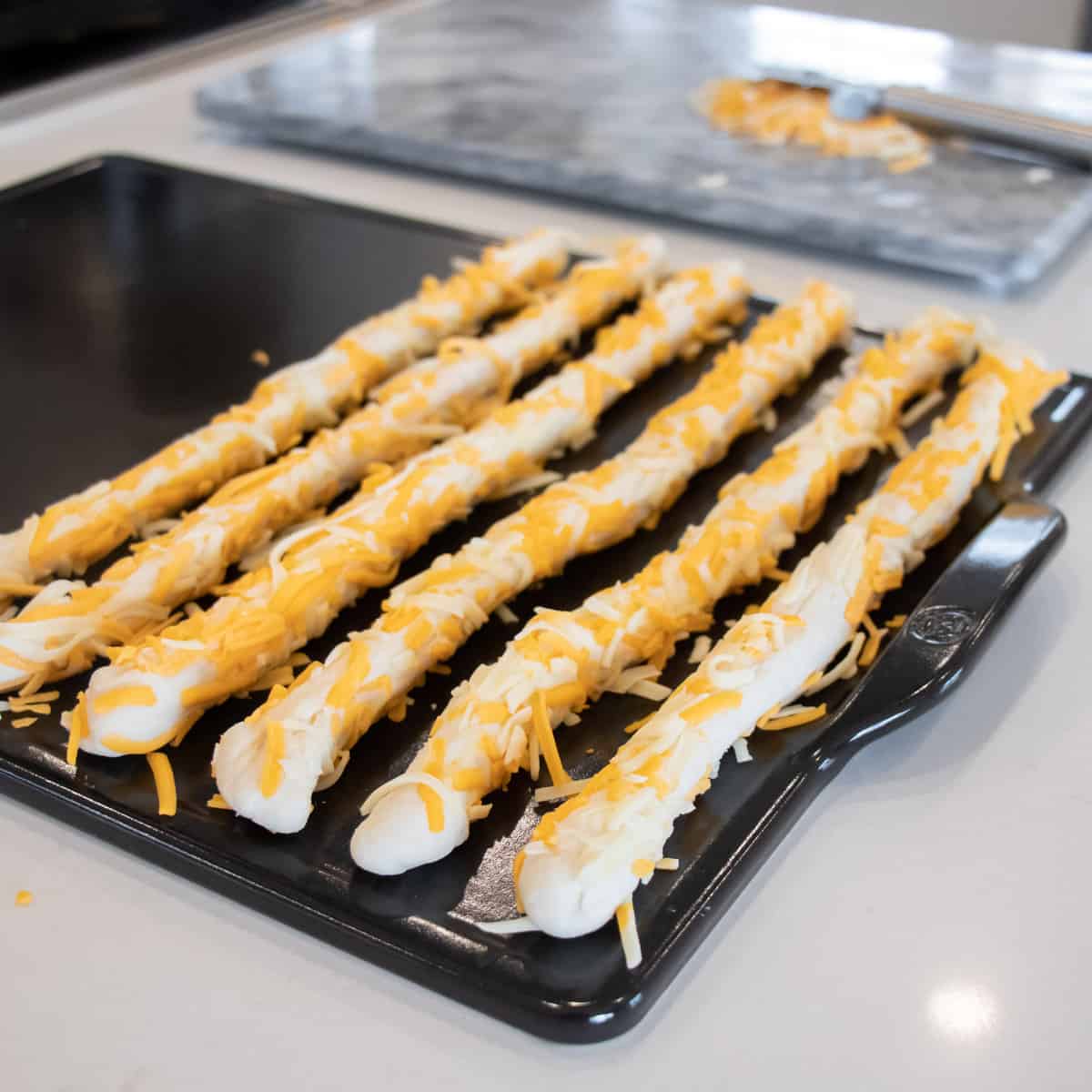 The rolled breadsticks resting on a baking sheet before they go in the oven.