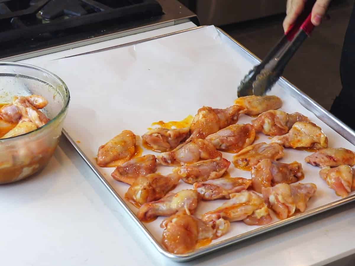Chicken wings placed on a baking sheet lined with parchment paper.