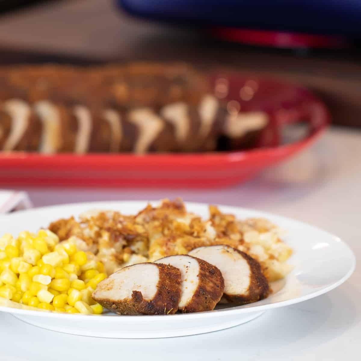 A dinner plate with pork, potatoes and corn.