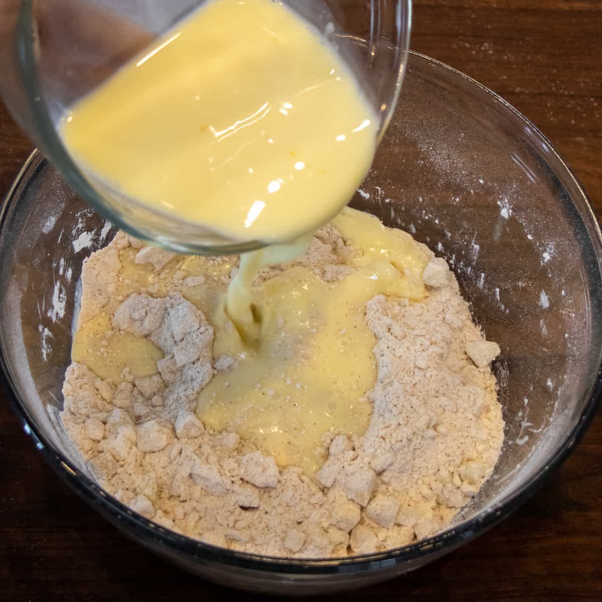 Pouring the milk and egg mixture into the bowl of dry ingredients.