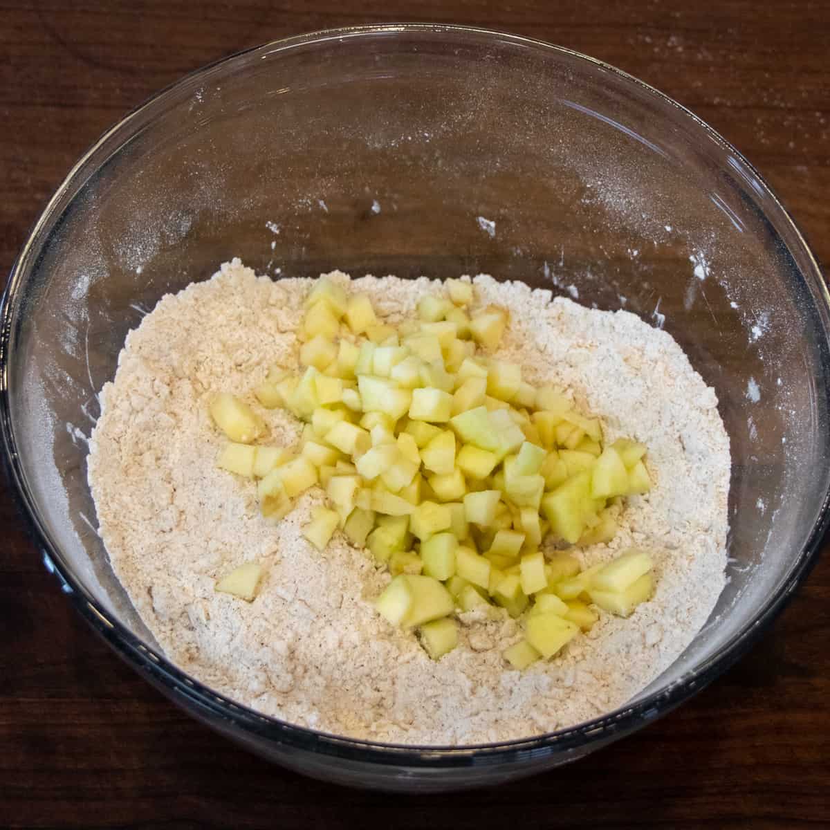 A bowl of the flour and butter mixture with the diced apples on top.