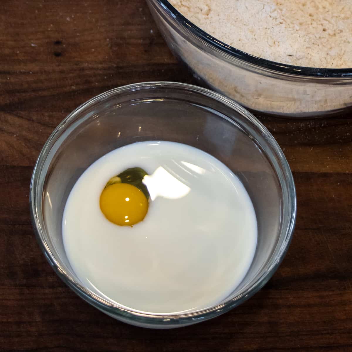 A glass bowl with an egg and milk.