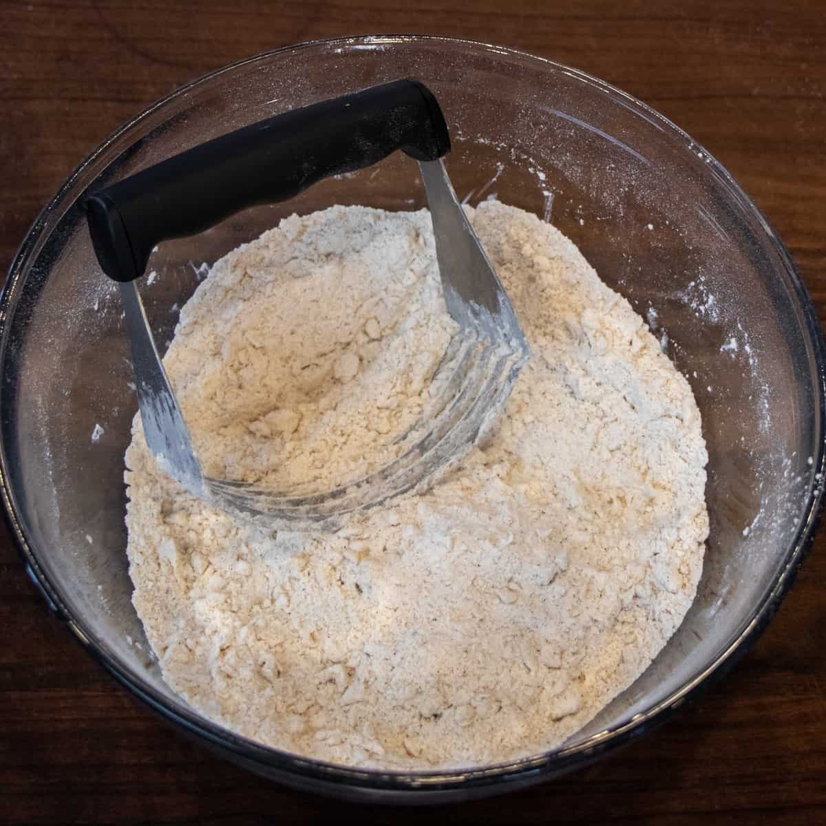 A bowl of dry ingredients with a pastry cutter that was used to cut in the butter.