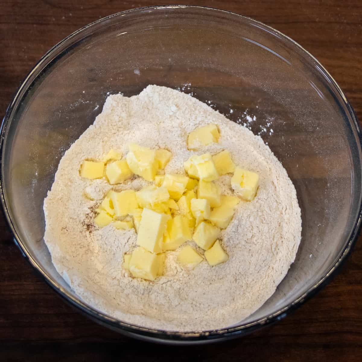 Cubes of cold butter in a glass bowl with the dry ingredients.