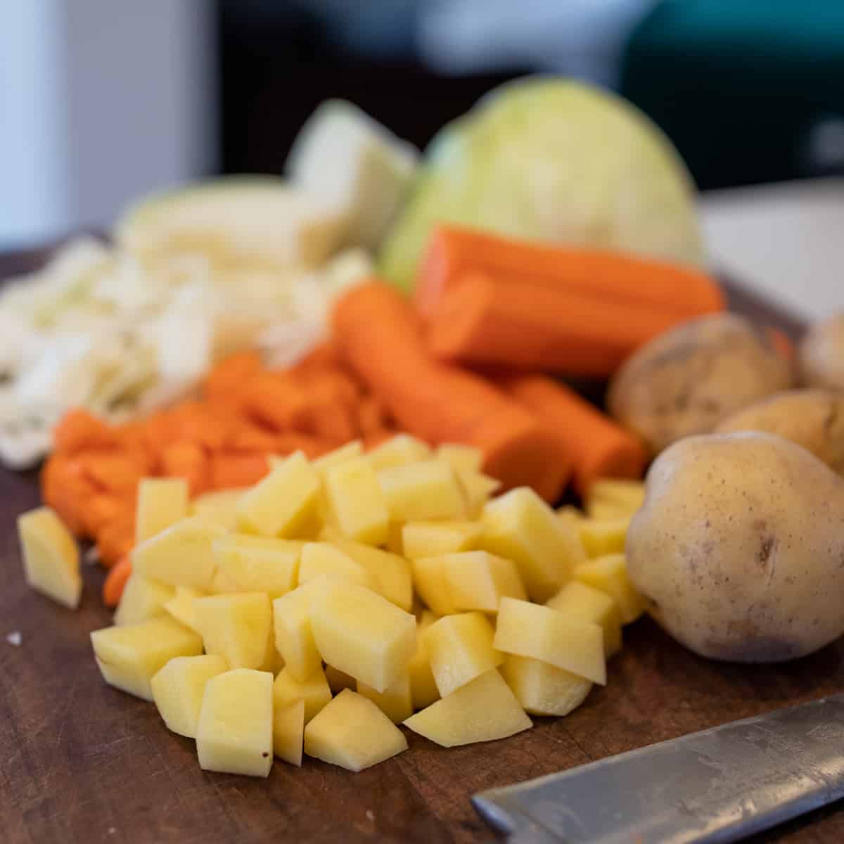 Potatoes, carrots and green cabbage cut into chunks.