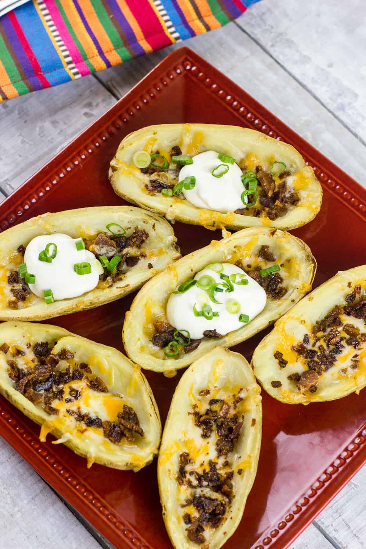 Overhead picture of potato skins on a red plate.